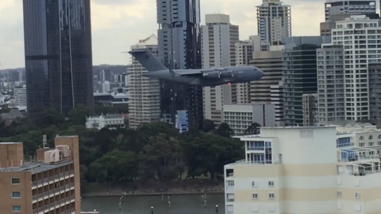 Stebėkite didžiulį karinį lėktuvą, skrendantį tarp pastatų Australijoje